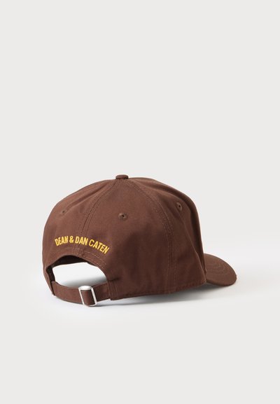 Casquette de baseball marron avec sangle ajustable et broderie jaune "DEAN & DAN CATEN" à l'arrière, présentée sur un fond clair uni.