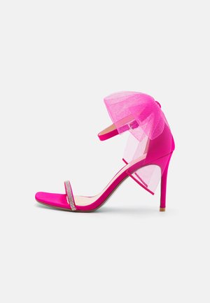 Sandalia de tacón alto en rosa fucsia con acento de tul de malla, punta abierta, tirante delgado en el tobillo y detalles de strass en la parte frontal.