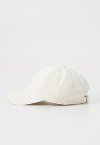 Wit corduroy baseballpet met een gebogen rand, verstelbare strap aan de achterkant en subtiele textuur. Klassiek ontwerp ideaal voor casual gebruik.