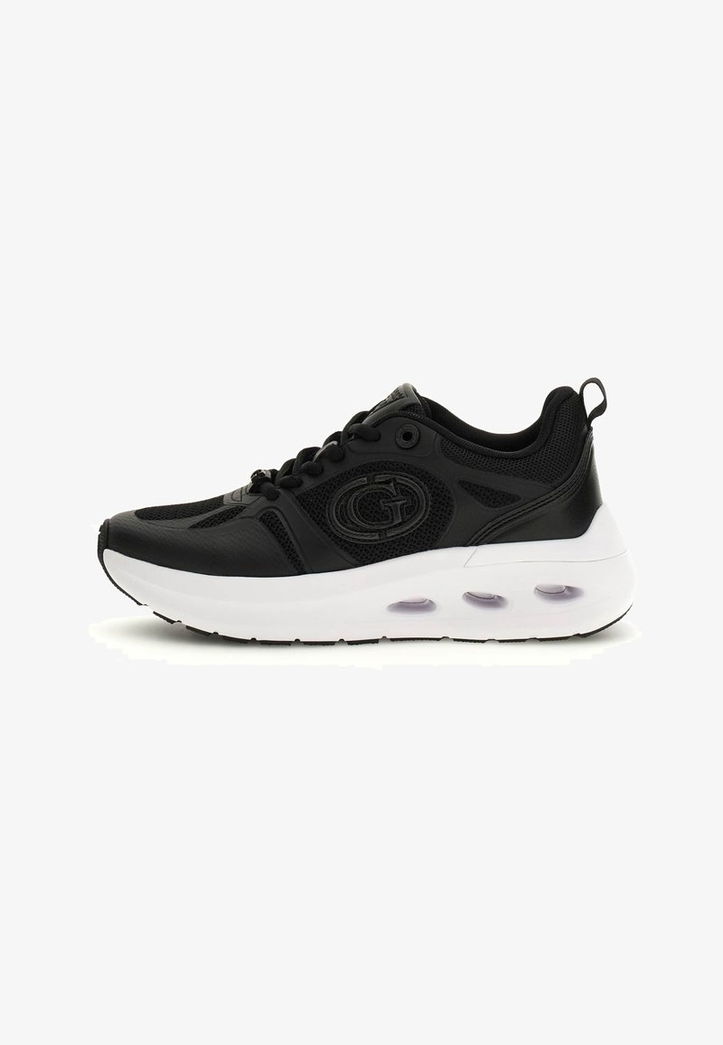 Baskets de sport noires avec empeigne en mesh et cuir, semelle blanche épaisse avec amorti à air visible, et logo sur le côté.