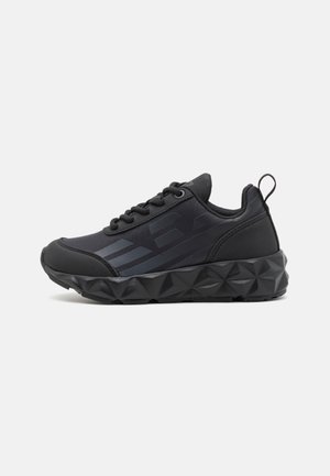 Czarny sportowy sneaker z teksturowaną, geometryczną podeszwą, sznurowaniem, wyściełanym kołnierzem oraz subtelnymi detalami w postaci pasków i logo po boku.