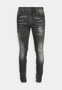 Jeans ajustados de denim negro con un acabado desgastado, detalles rasgados, cinco bolsillos y un acento rojo en el botón.