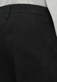 Zwarte denim broek met een achterzak, met een gladde textuur en rechte snit. Zichtbare stiksels en een klassiek ontwerp van de tailleband.