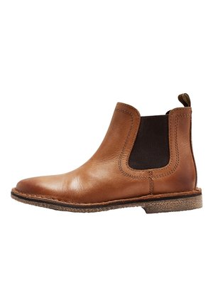 Botte Chelsea en cuir brun avec panneaux latéraux élastiques, semelle texturée et bout rond. Présente une couture et une tirette à l'arrière.