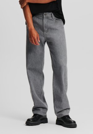 Gray denim jeans with a loose fit, five-pocket design, and a zip fly. Worn with black lace-up boots. Smooth texture, casual style.