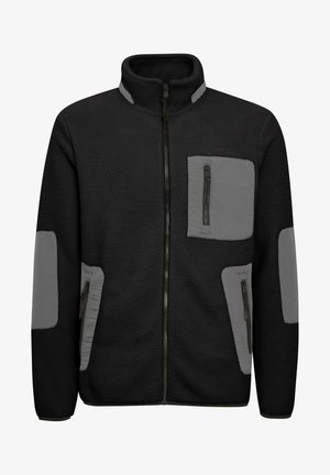 Melna vilnas jaka ar pelēkiem akcentiem. Iekļauj pilnu rāvējslēdzēju, divas rāvējslēdzēja kabatas un teksturētu audumu ar gludām paneļiem uz piedurknēm.