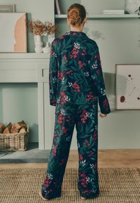 Námořnický pyžamový set s květinovým vzorem v červené a zelené barvě. Uvolněný střih s dlouhými rukávy a kalhotami. Měkká tkanina, zakončené lemy a detaily na knoflících.