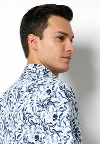 Kurzarmhemd mit weißem Hintergrund und floralem Muster in Blau und Marineblau. Standardkragen und glatte Stofftextur.