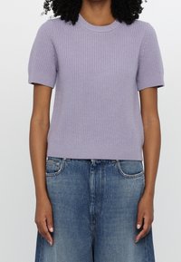 Maglione short-sleeve in lavanda a maglia con texture a coste, scollo rotondo e orlo aderente, abbinato a jeans boyfriend azzurri.