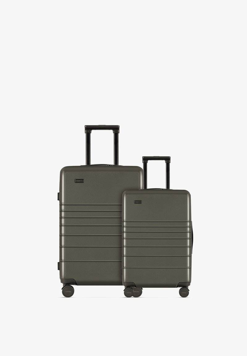 Twee harde koffers in donkergroen, met een gestructureerd oppervlak, horizontale groeven en een uitschuifbare handgreep op elke koffer.