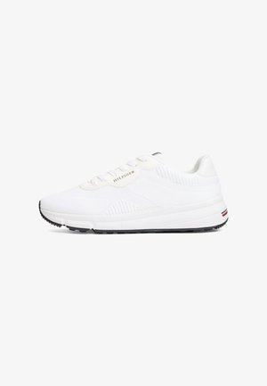 Valge sportlik toss, millel on võrgusilmast ülemine osa, lame pael ja minimalistlik disain. Omab musta tallat ja peent logo detaili külgedel.