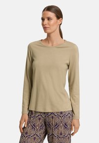 Top de manga larga en un suave tejido de color verde oliva claro con escote redondo. Combinado con pantalones de color beige y púrpura con un diseño floral.
