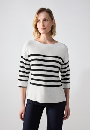 Maglione bianco lavorato a maglia con righe orizzontali nere, scollatura a barca e maniche a tre quarti, abbinato a pantaloni scuri.