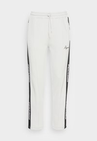 Vita sweatpants med svarta sidopaneler med text. Elastisk midja med snörning. Slät material och smal passform vid anklarna.