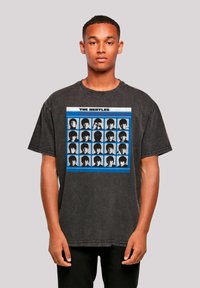 Black oversized T-shirt featuring a graphic print of multiple black-and-white images with blue and red accents, round neckline, and short sleeves.