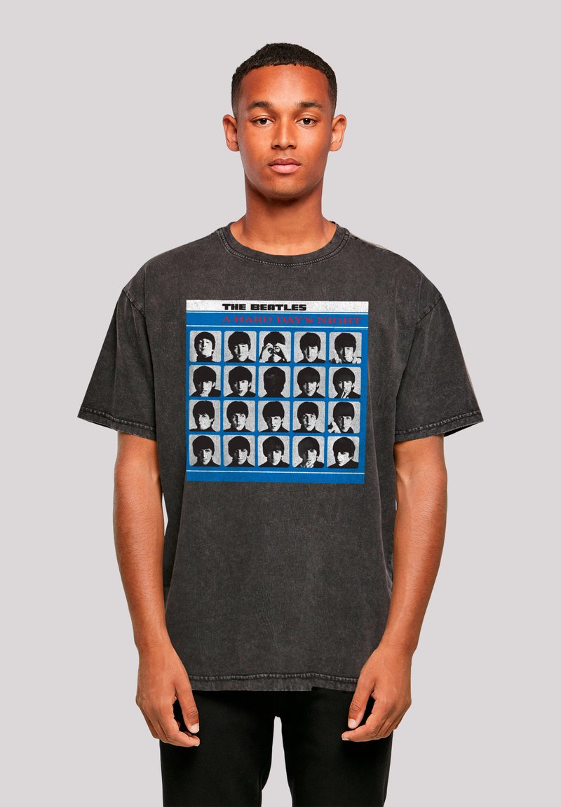 Black oversized T-shirt featuring a graphic print of multiple black-and-white images with blue and red accents, round neckline, and short sleeves.