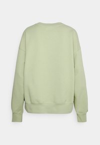 Sudadera verde claro, tela suave, corte holgado, hombros caídos, puños y dobladillo acanalados, diseño minimalista, sin logos ni patrones visibles.