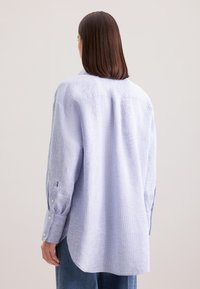 Camicia a maniche lunghe a righe blu e bianche in tessuto leggero, con orlo curvo, polsini con bottoni e vestibilità rilassata.