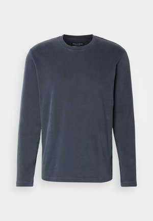 Garā piedurkņu tumši zila krekls, kas izgatavots no mīksta kokvilnas. Tam ir apaļa kakla izgriezums un taisna griezuma siluets. Minimalistisks dizains, nav papildu rakstu vai akcentu.