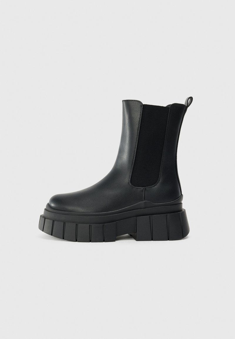 Black ankle boots made of smooth leather with elastic side panels, a thick, ridged platform sole, and a pull tab at the back.
