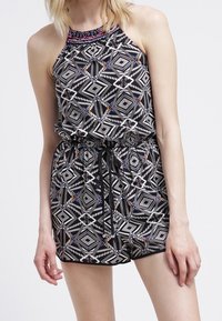 Mono negro con estampado de diamantes y diseños geométricos. Presenta un escote halter, cintura ajustable con cordón y cuentas de colores en los acentos.