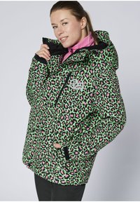 Grüne gesteppte Jacke mit pinkem und schwarzem Leopardenmuster, ausgestattet mit hohem Kragen, Reißverschlusstaschen und einem Logo-Akzent auf der Brust.