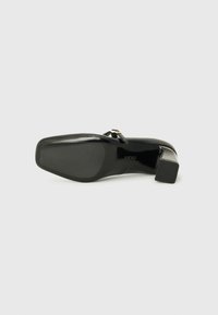 Black high-heeled shoe with a smooth leather upper, square toe, silver buckle detail, and textured rubber sole for grip.