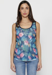 Débardeur floral avec fond bleu, présentant des motifs tropicaux roses et verts, encolure dégagée et accents texturés.