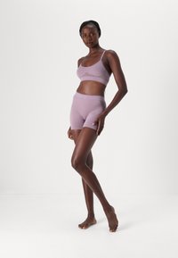 Lys lilla sømløs sports-bh og shorts-sett med tynne stropper, teksturerte detaljer og en tettsittende design. Myk, elastisk stoff.