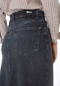 Jeansnederdel i mørkegrå med høj talje, har to baglommer og en mærket talje. Stoffet har en glat overflade.