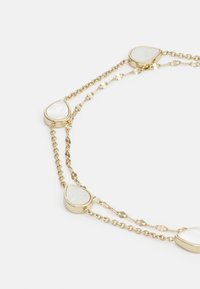 Collar de cadena de oro que presenta piedras blancas en forma de lágrima espaciadas a lo largo de los eslabones, mostrando una mezcla de acabados lisos y texturizados.