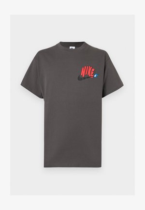 Σκούρο γκρι κοντομάνικο μπλουζάκι με κόκκινο κείμενο "NIKE", μαύρο λογότυπο Swoosh και μικρή μπλε φλόγα στην αριστερή πλευρά του στήθους.