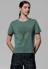 Grünes Baumwoll-T-Shirt mit kurzen Ärmeln, das ein dunkelgrünes Baumgrafikdesign in der Mitte aufweist. Rundhalsausschnitt, lockere Passform.