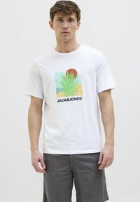 Camiseta de algodón blanca con un diseño gráfico colorido que presenta una planta verde, un sol rojo y el texto "JACK & JONES". Mangas cortas y cuello redondo.