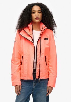 Lys neon pink vandtæt jakke med hætte, frontal lynlås, to sidelommer og logo-detail på brystet. Blød tekstur, afslappet pasform.