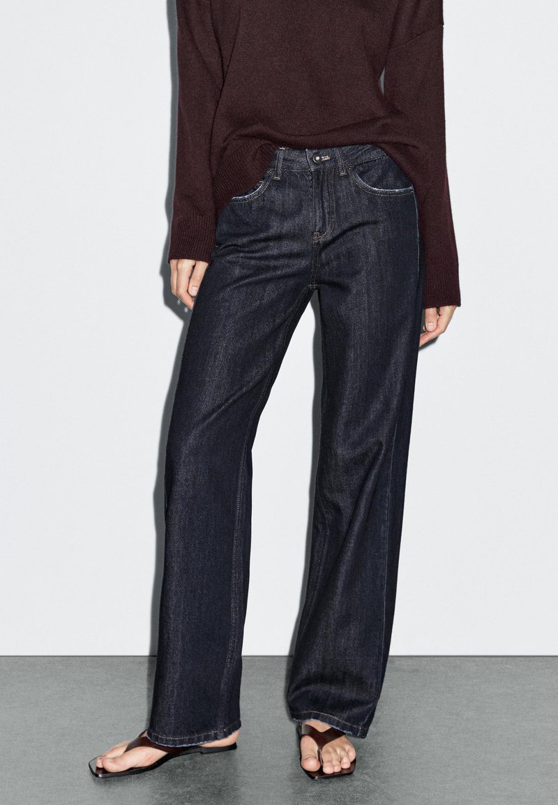 Dunkelblaue weite Jeans aus Denim, mit classic fünf Taschen-Design, Reißverschluss und Knopfverschluss.