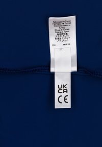 Tessuto blu navy con una texture liscia e un'etichetta di cura. L'etichetta include testo multilingue, marchi UKCA e CE.