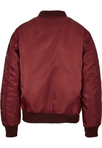 Burgundská bomber bunda s hladkým, lesklým povrchem, žebrovaným límcem a manžetami. Záda mají jednoduchý, nezdobený design.