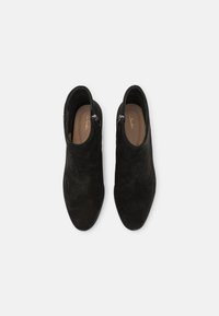 Schwarze Wildleder-Stiefeletten mit spitzem Zehenbereich, seitlichem Reißverschluss und beigem Innenfutter. Glatte Textur mit einem subtilen Glanz.