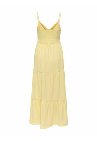 Robe maxi jaune à bretelles spaghetti, corsage smocké et jupe à volants. Tissu doux avec une texture lisse, conçu pour le confort.