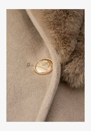 Beige wool coat with a soft fur collar, featuring a gold button with engraved detailing. The texture appears smooth and plush.