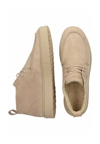 Stivaletti alla caviglia in suede beige con suola in gomma testurizzata, lacci sul davanti e un morbido rivestimento in pelliccia sintetica. Presentano una piccola linguetta sul retro.