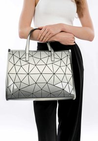 Silberne geometrische Umhängetasche mit glänzender Oberfläche, die ein dreieckiges Muster, doppelte Griffe und eine strukturierte rechteckige Form aufweist.