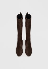 Botas altas de camurça castanhas com bicos apontados, apresentando fechos laterais e uma textura suave. O design enfatiza uma silhueta ajustada.