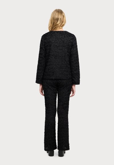 Zwevend zwart textieloutfit met een langemouwen top en uitlopende broek, met een pluizige afwerking en een rechte silhouet.