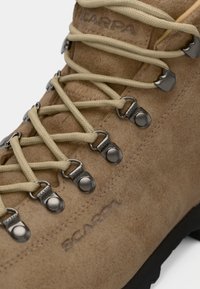 Tanfarbene Wildleder-Wanderschuhe mit beigen Schnürsenkeln, Metallbeschlägen und SCARPA-Branding. Verfügt über ein robustes Design und eine strukturierte Oberfläche. Schwarze Sohle sichtbar.