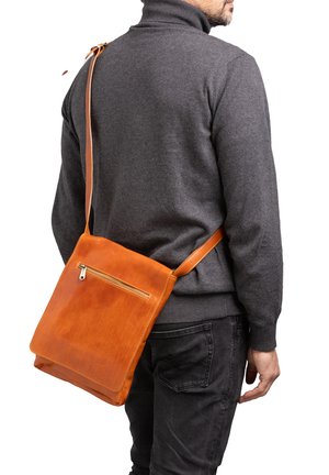 Borsa a tracolla in pelle marrone con tasca frontale con zip, design piatto, tracolla regolabile e superficie liscia, indossata sopra un maglione grigio.