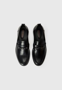 Sorte skinnloafers med en blank finish, med kjedeaccent, broderte detaljer og gummisåle. Logo synlig på innersålen.