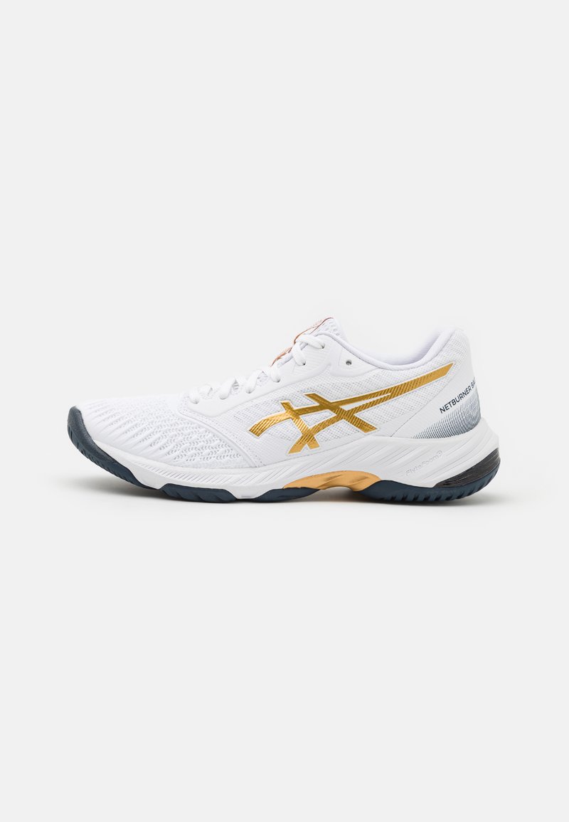 Chaussure de sport blanche avec une tige texturée, des accents dorés et une semelle en caoutchouc sombre. Elle dispose d'un système de laçage et d'une semelle intermédiaire rembourrée pour un soutien.