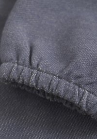 Navyblauwe textiel met een gestructureerd oppervlak en elastische gathers. Heeft gestikte randen en een consistent patroon over de stof.